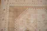 Distressed vintage Oushak carpet with abrashed ivory and geometric wave border.