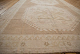 Distressed pile texture with geometric motifs and abrashed neutral tones on this Oushak rug.