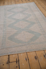 Faded ivory and dusty blue stepped diamond pattern on distressed vintage Oushak rug with even wear.