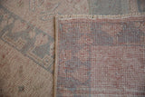 Distressed ivory and dusty blue pile, visible hand-knotted Oushak reverse, and fringe.