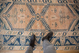 Distressed Melas rug with cobalt blue hook and latch motifs and even pile wear.