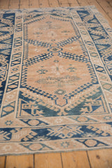 Distressed beige field and cobalt blue geometric motifs on a vintage Melas rug.