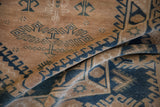 Close-up of distressed Melas rug showcasing beige field, cobalt blue hook and latch motifs.