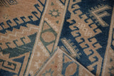 Distressed hand-knotted Melas rug pile in beige, cobalt blue, dusty teal, with foundation showing.