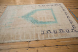 Distressed Oushak rug corner with aqua blue prayer motifs and dark slate border.