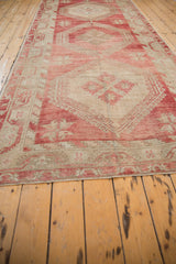 Perspective view down the length of a distressed Oushak runner with raspberry red medallions.