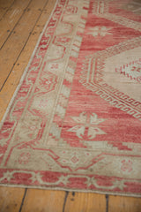 Starburst motifs and low pile on the raspberry and ivory border of a vintage distressed Oushak runner.