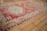 Angled detail view of a geometric medallion and the heavily abrashed raspberry red field of a vintage Oushak runner.