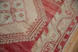 Hook and latch border detail on a distressed Oushak rug with abrashed raspberry red and ivory pile.