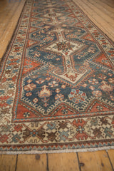 Long perspective view of a distressed Hamadan runner highlighting the repeating shield medallions.