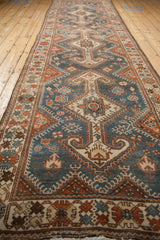 Angled perspective along a vintage Hamadan runner showing repeating shield arrowed medallions.