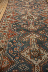 Angled view of a distressed Hamadan runner's geometric pattern in dusty blue and madder red.