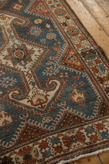 Detail of the geometric medallion with arrowed finials on a distressed Hamadan rug in dusty blue.