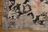 Vintage Qom pictorial rug fragment: worn charcoal and blush motifs, exposed foundation, and patched border.