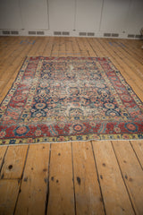 Worn navy field with sprawling boteh paisley and ornate dusty cherry red border detail.