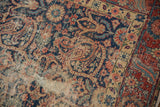 Foundation showing through the worn navy blue field of the vintage Persian rug.