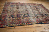 Worn corner of a Vintage Northwest Persian rug, displaying red border and navy boteh field.
