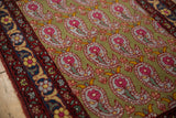 Detail of repeating boteh paisley motifs on a sage green field next to the arabesque floral border.