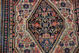 Ivory field with blush Herati motifs, navy stepped medallion edge, and visible knot heads.