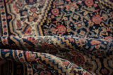 Detailed navy, ivory, blush Herati motifs on the evenly worn folded vintage Senneh rug.
