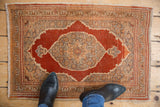 Overhead view of a vintage Tabriz rug mat shown for scale, with a rust and silver medallion.