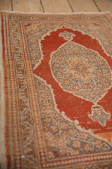 Angled detail of the vintage Tabriz rug's floral vine border against its rust-colored field.
