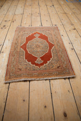 Overhead view of a vintage Tabriz rug mat showing its rust medallion and intricate sand-colored borders.