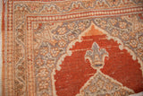 Rust-colored corner spandrel with a trefoil finial and floral borders on a vintage Persian Tabriz rug.