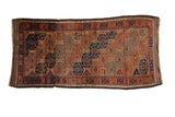 Antique Belouch rug runner with diagonally layered geometric guls in camel, rust, and navy blue.