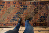 A standing perspective showing the scale of an antique Belouch runner's geometric guls.