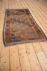 Antique Belouch rug runner from an angle, showing its full length and geometric earthen palette.
