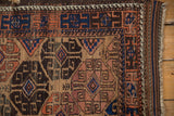 Corner detail of an antique Belouch rug with its running wave motif border and intact side cord.