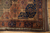 A detailed view of the running wave motif border and side cord selvage of an antique Belouch rug.