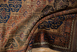 Close view of the low pile and geometric guls in camel, navy blue, and madder root on an antique Belouch rug.