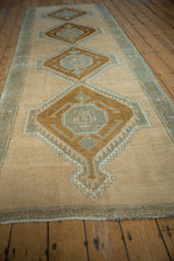 Distressed Oushak runner with interconnected medallions showing faint foundation in ivory, bronze, slate.