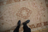Vintage distressed Oushak rug with pale blush, ivory, copper floral medallion and vinery.