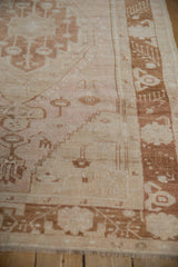 Distressed Oushak rug side border with copper motifs on blush field, showing even wear.