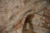 Distressed Oushak rug detail showing faded blush, ivory, copper pattern, with visible knot heads.