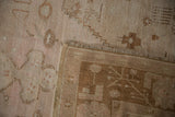 Distressed pale blush and ivory Oushak pile with foundation showing, folded to reveal woven reverse.