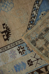 Distressed Oushak rug's worn pile, showing even wear and blue geometric motifs.