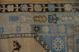 Distressed vintage Oushak rug detail: ivory germinating plant motif, pale blue banded borders.