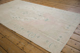 The soft, time-softened tones of a distressed Oushak rug runner seen from an angle.