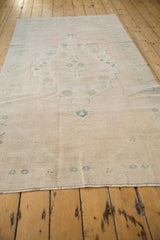Angled view down the length of a distressed Oushak runner with a soft, faded palette.