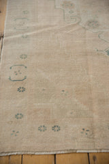 Low hand-knotted pile of a distressed Oushak rug with even wear and a sandy texture.
