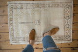Distressed vintage Oushak rug with soft ivory and beige tones, showing even low pile texture.