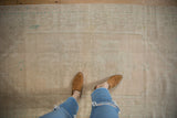 Faded ivory and cream distressed Oushak rug with subtle pale green medallion and spandrel designs.