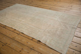 Distressed vintage Oushak rug showing its even wear, faint patterns, and soft beige tones.