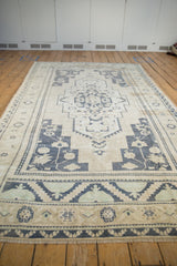Distressed Oushak rug end featuring navy blue, seafoam green geometric patterns and fringe.