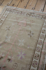 Distressed beige field and worn pile texture on a vintage Oushak rug with mauve pinwheel border.