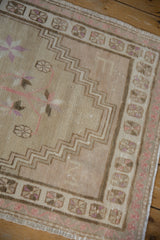 Distressed Oushak rug detail: beige field, mauve pinwheel main border, stepped zig-zag pattern.